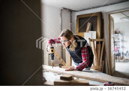 Young woman worker in the carpenter workroom. Young woman worker in the carpenter workroom. 36745452