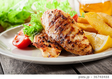 Grilled chicken breasts served with fries Grilled chicken breasts served with fries 36748488