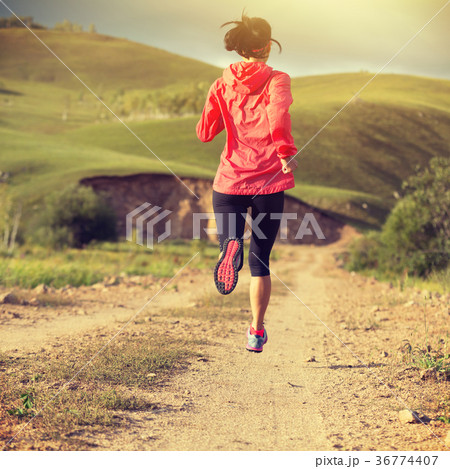 sporty woman trail runner running on dirt road sporty woman trail runner running on dirt road 36774407