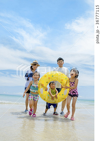 夏の海辺で浮輪を持って遊ぶ5人家族 36777115