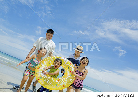 夏の海辺で浮輪を持って遊ぶ5人家族 36777133