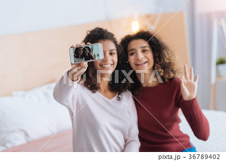 Cheerful girl taking self portraits together Cheerful girl taking self portraits together 36789402