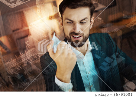 Irritated man in suit squeezing paper in his hands Irritated man in suit squeezing paper in his hands 36791001