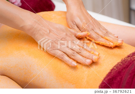 Spa Therapist applying orange scrub salt on back Spa Therapist applying orange scrub salt on back 36792621