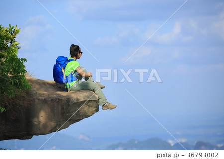 Young woman hiker sit on mountain top cliff edge 36793002