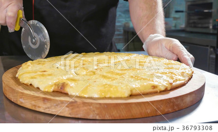 Chef cutting hot ready pizza by rolling pizza Chef cutting hot ready pizza by rolling pizza 36793308