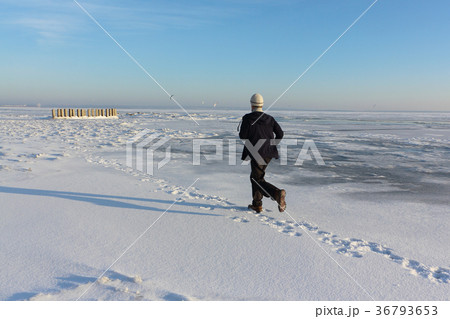 Mature man running on ice of a frozen river Mature man running on ice of a frozen river 36793653