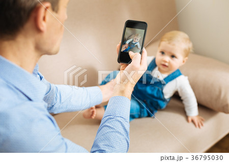 Attentive father taking a photo of his cute baby 36795030