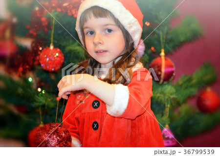 Little girl in Santa's dress by the Christmas tree Little girl in Santa's dress by the Christmas tree 36799539