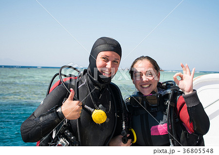 two smiling divers in wet suits show ok.azure sea 36805548