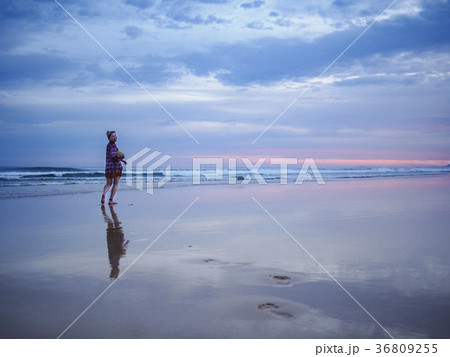 Australia, New South Wales, Woman standing on beach at dusk 36809255