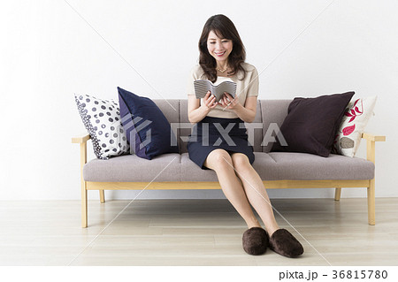 ソファに座って読書を楽しむミドル女性の写真素材