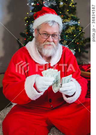 Santa claus sitting on the floor and counting cash at home Santa claus sitting on the floor and counting cash at home 36834587