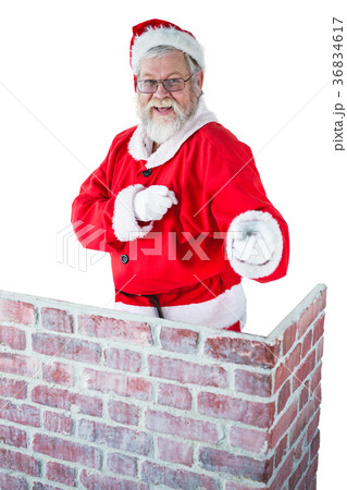 Santa claus standing behind the chimney and pointing against white background 36834617