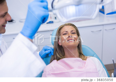 Dentist adjusting electric light while patient sitting on chair Dentist adjusting electric light while patient sitting on chair 36835050