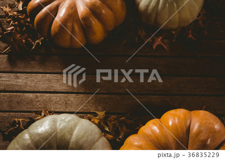 Autumn leaves by pumpkins on wooden table Autumn leaves by pumpkins on wooden table 36835229