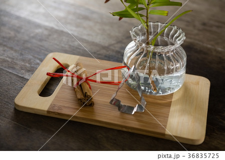 Wrapped cinnamons, cookie cutter and pot plant on chopping board 36835725
