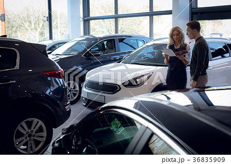 Saleswoman reading brochure while standing by customer 36835909