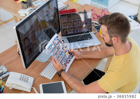 Male executive looking at photos at desk 36835982