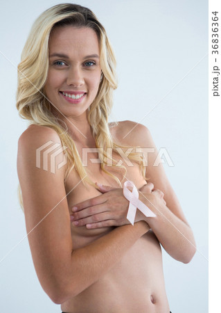 Portrait of smiling woman covering breast with pink ribbon on hand 36836364