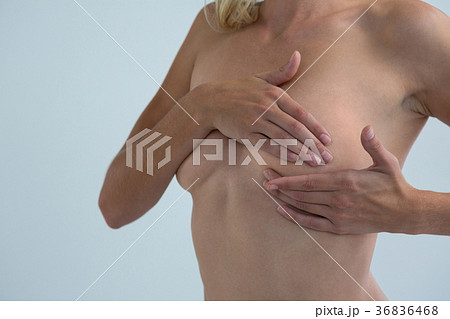 Mid section of young woman touching breast while examining lumps Mid section of young woman touching breast while examining lumps 36836468