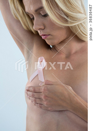Woman covering breast while looking at pink ribbon Woman covering breast while looking at pink ribbon 36836487