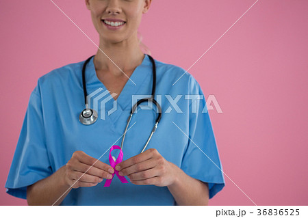 Mid section of happy female doctor in scrubs showing Breast Cancer Awareness ribbon Mid section of happy female doctor in scrubs showing Breast Cancer Awareness ribbon 36836525