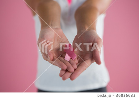 Mid section of young woman showing Breast Cancer Awareness ribbon Mid section of young woman showing Breast Cancer Awareness ribbon 36836633