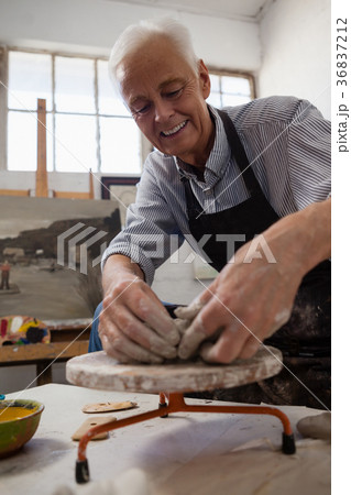 Smiling senior man molding clay 36837212