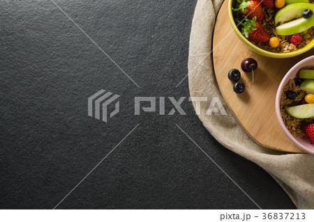 Bowls of breakfast cereals with fruits on chopping board 36837213