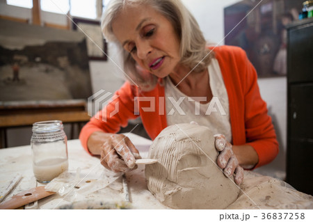 Attentive senior woman shaping a molded clay 36837258