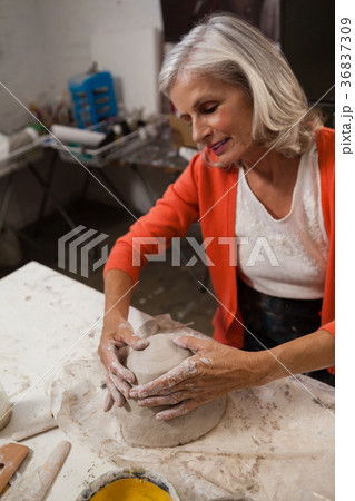 Attentive senior woman molding clay 36837309