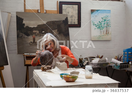 Attentive senior woman making a clay sculpture 36837537