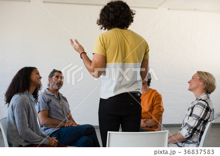 Man gesturing while discussing with friends sitting on chair Man gesturing while discussing with friends sitting on chair 36837583