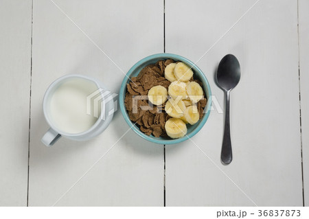 Wheat flakes and banana slice in bowl with milk jug Wheat flakes and banana slice in bowl with milk jug 36837873