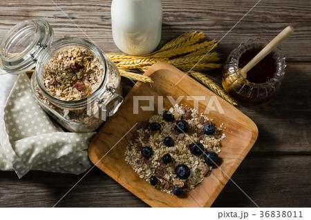 Breakfast cereals and jar of honey on wooden table 36838011