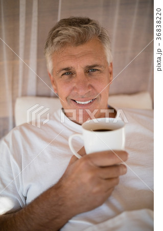 Portrait of happy man having coffee on bed Portrait of happy man having coffee on bed 36838220