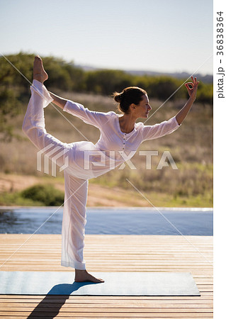 Woman practicing yoga on at poolside 36838364
