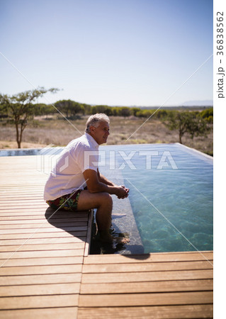 Thoughtful man sitting near pool side Thoughtful man sitting near pool side 36838562
