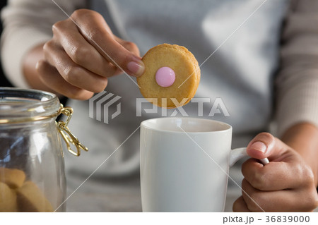 Woman dipping a cookie into a mug 36839000
