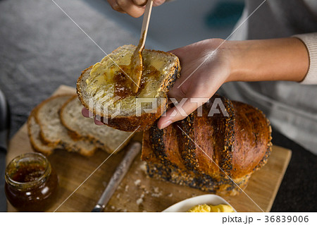 Woman applying jam over multigrain bread slice Woman applying jam over multigrain bread slice 36839006