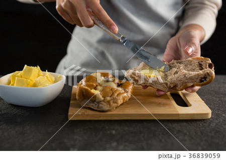 Woman applying butter over multigrain bun slice 36839059