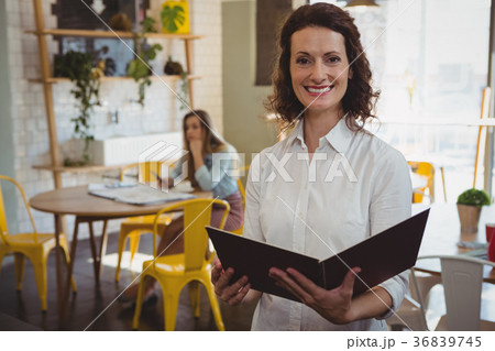 Portrait of confident waitress with menu in cafe 36839745