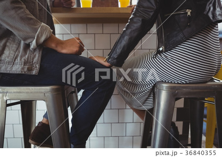 Low section of couple on stool in cafe Low section of couple on stool in cafe 36840355