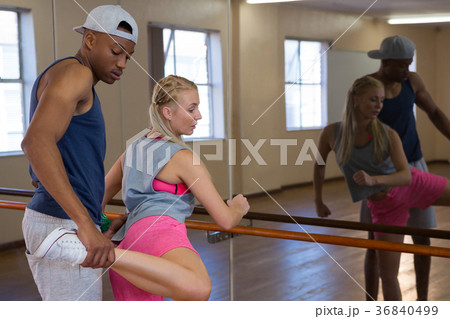 Man assisting female friend in stretching leg on barre Man assisting female friend in stretching leg on barre 36840499