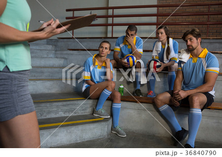 Mid section of coach standing by volleyball players Mid section of coach standing by volleyball players 36840790
