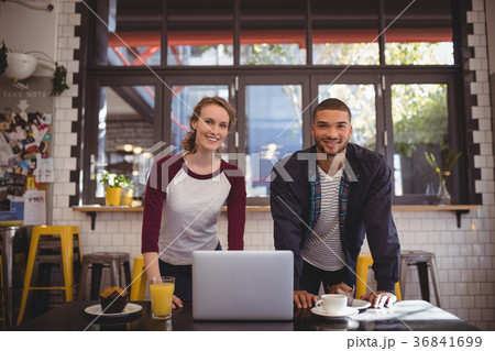 Portrait of smiling young man and woman standing at coffee shop 36841699