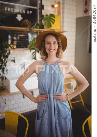 Portrait of smiling woman standing with hands on hip at coffee shop 36842037