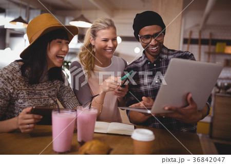 Man showing laptop to cheerful female friends at coffee shop 36842047