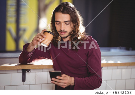 Young handsome man drinking coffee while using smartphone Young handsome man drinking coffee while using smartphone 36842158